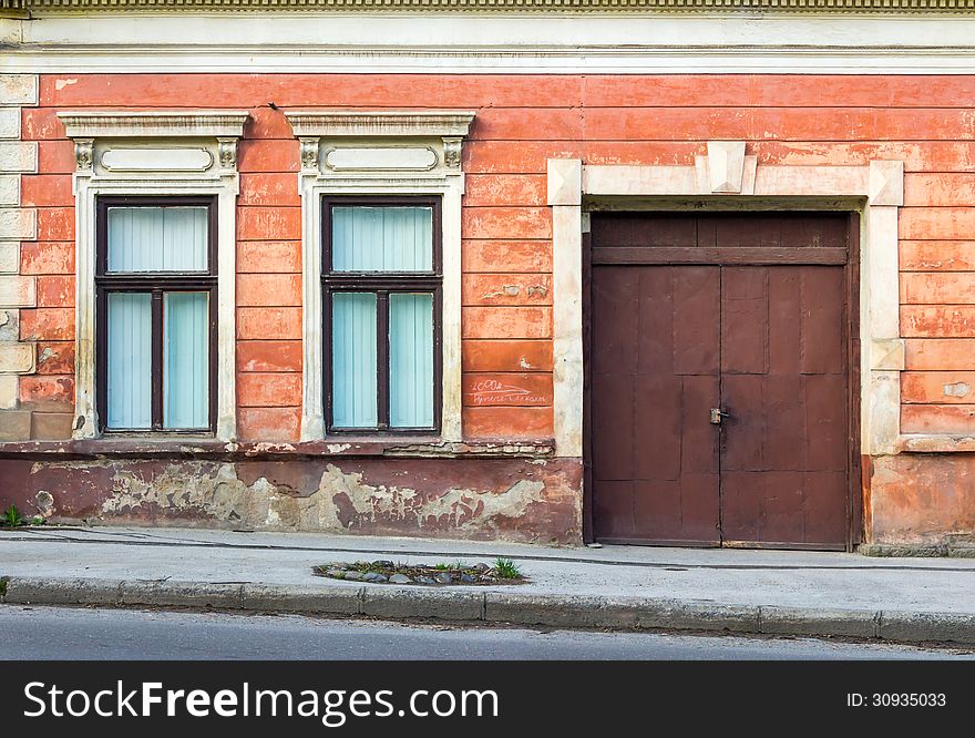 Two windows and a large metal door on the facade of an old building. Two windows and a large metal door on the facade of an old building