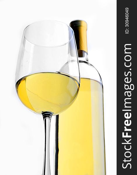 A glass of white wine with a wine bottle