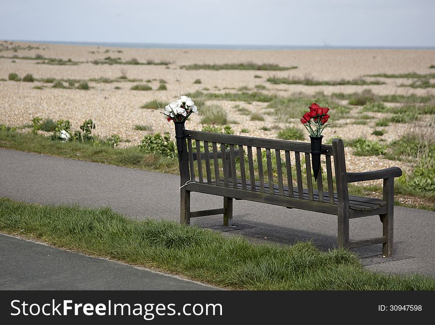 Empty bench with memorial flowers on deserted path on Kent coast. Empty bench with memorial flowers on deserted path on Kent coast