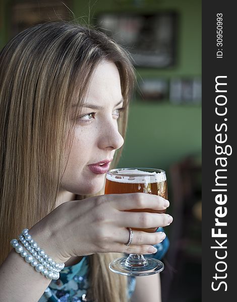 Blonde Woman with Beautiful Blue Eyes Drinks a Goblet of Beer