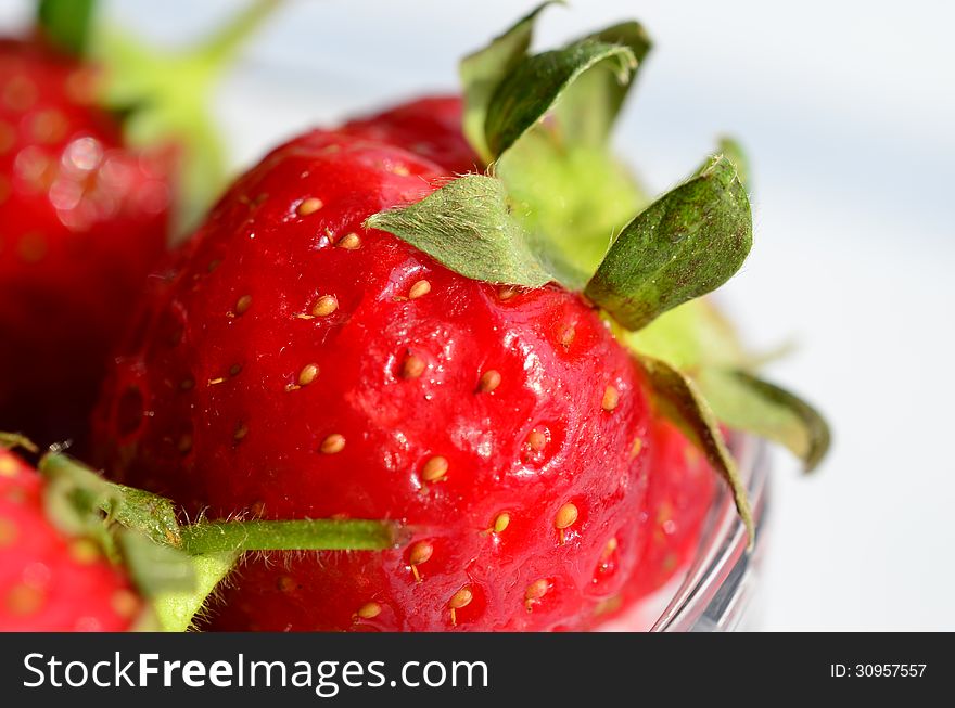 Macro shot of strawberries in glass bowl isolated on white, shallow depth of field