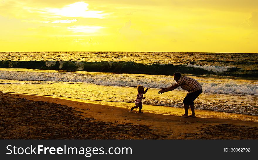 Father and daughter playing together on the beach at sunset