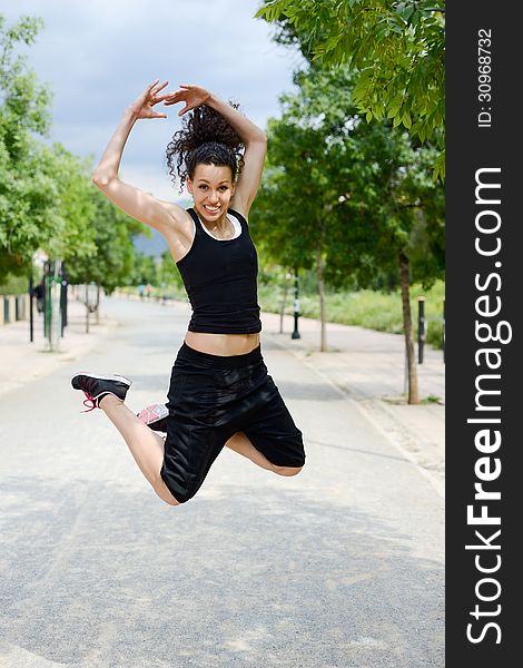 Portrait of young woman in sports doing exercise, jumping, in urban background. Portrait of young woman in sports doing exercise, jumping, in urban background