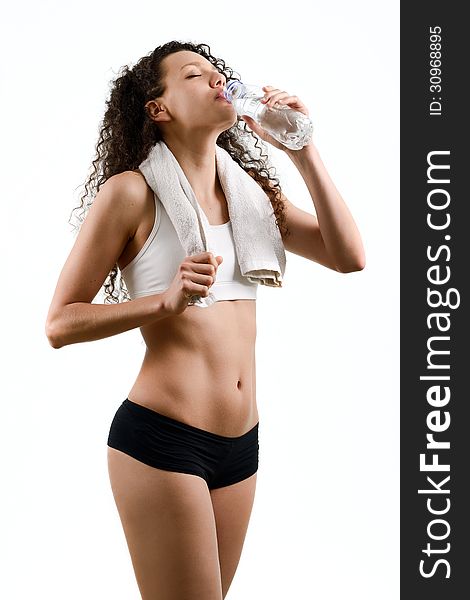 Young woman wearing sport clothes and drinking water on white ba