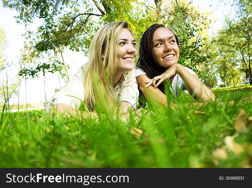 Two beautiful girls rest on a green glade. Two beautiful girls rest on a green glade