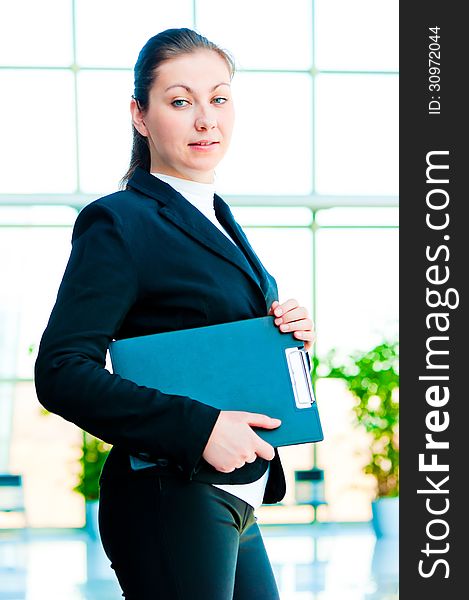 A smiling girl holding a manager office folder on office background