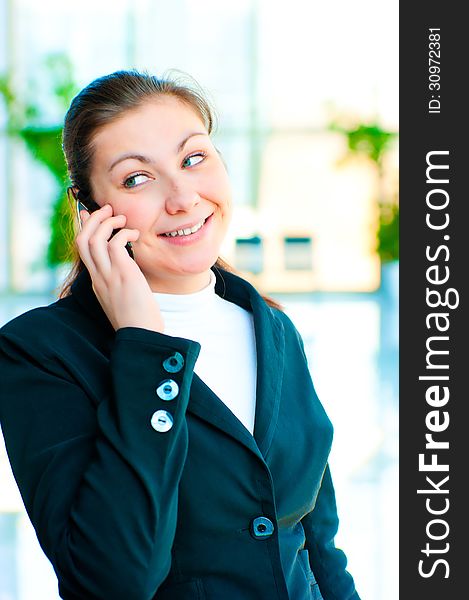 Young happy business woman talking on the phone on office background