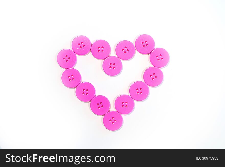 Pink buttons lined up in heart shape. Pink buttons lined up in heart shape