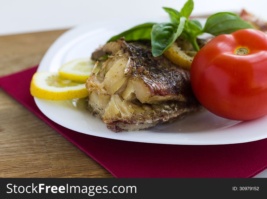 Served grilled fish with lemon and basil with tomato