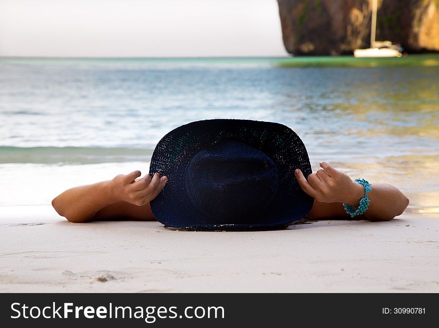 The girl in a hat lies on a beach. The girl in a hat lies on a beach