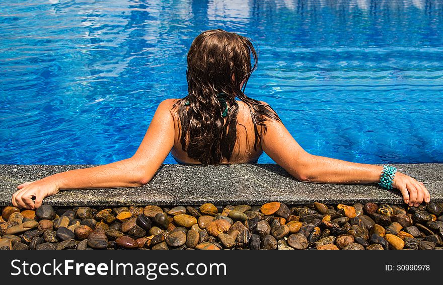 The young woman sits in the pool. The young woman sits in the pool