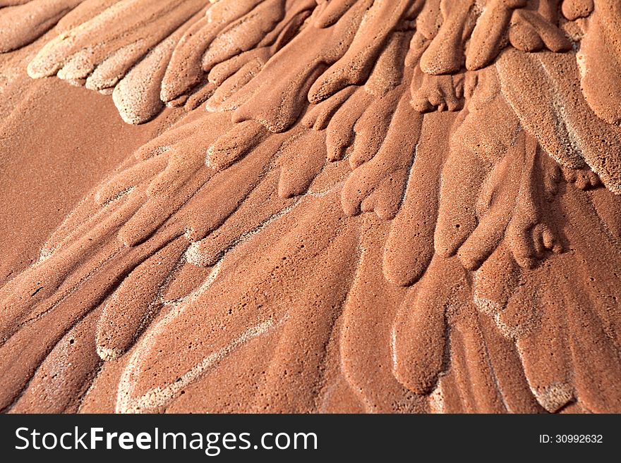 Wet red sand. Water has etched a pattern into sand. Wet red sand. Water has etched a pattern into sand