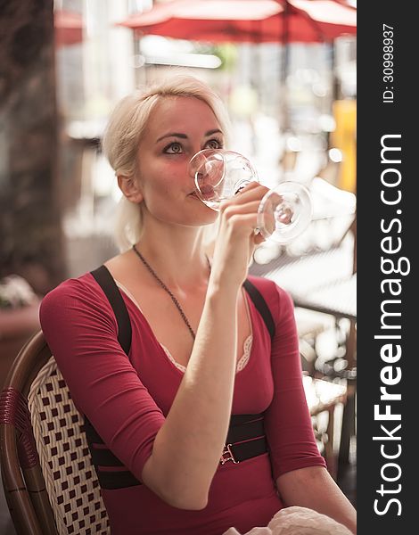 Portrait of a beautiful blond woman shot outdoors at a cafe. She has green eyes and bleached blond hair and is holding a glass of white wine. Portrait of a beautiful blond woman shot outdoors at a cafe. She has green eyes and bleached blond hair and is holding a glass of white wine.