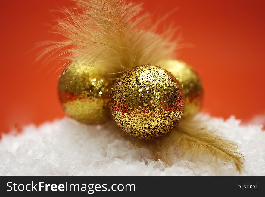 Three golden decorations on a pile of fake snow.