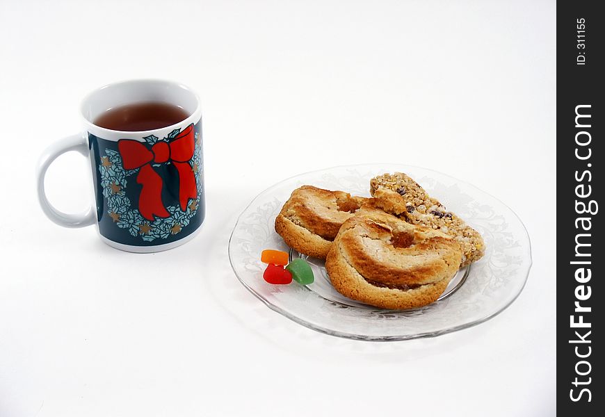 Herbal tea in a Christmas-style mug with assorted snacks on a glass plate. Herbal tea in a Christmas-style mug with assorted snacks on a glass plate