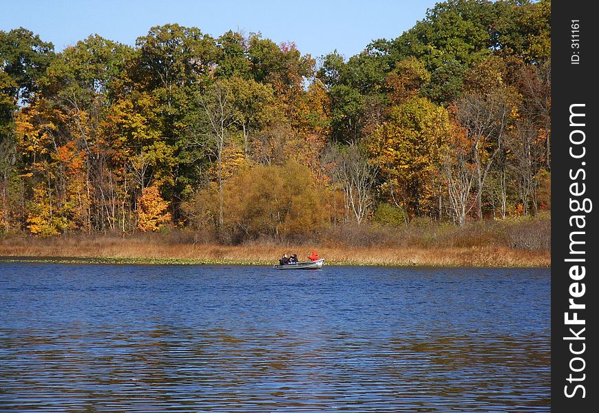 Autumn lake with rowboat on far side. Autumn lake with rowboat on far side