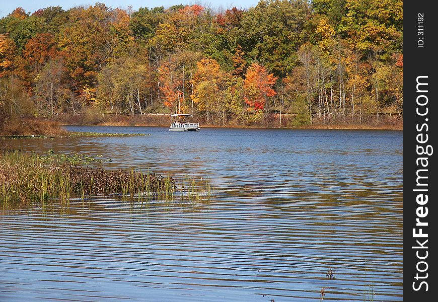 Pontoon boat approaching from far end of lake. Pontoon boat approaching from far end of lake