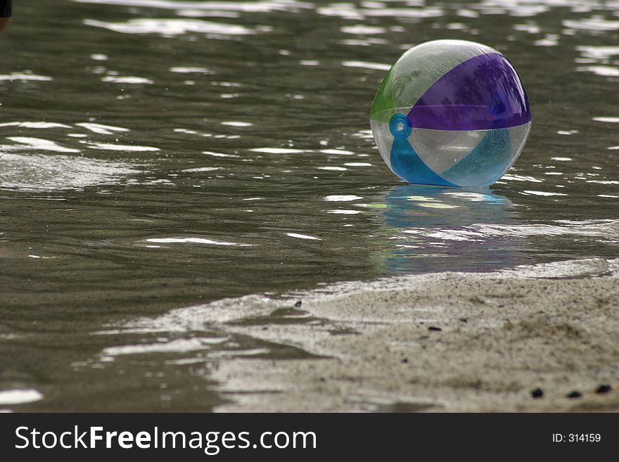 Beach ball floating along waters edge