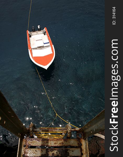 Orange boat tied to stairs floating on beautiful ocean. Orange boat tied to stairs floating on beautiful ocean