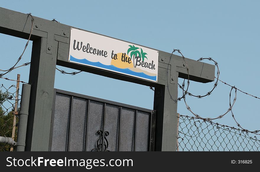 Sign Over entrance To Beach Has Iron gate And Razor wire. Sign Over entrance To Beach Has Iron gate And Razor wire