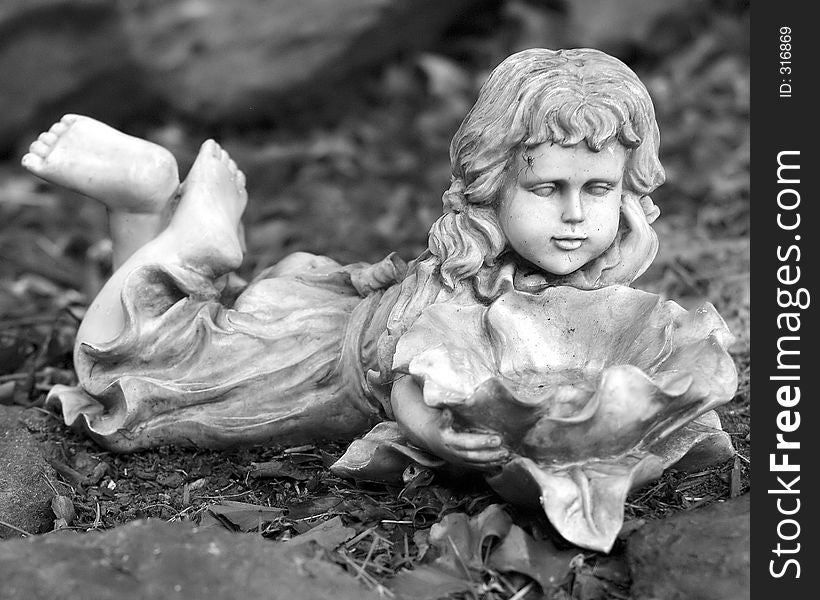 Close up image of a small statue of a little girl in a garden. Close up image of a small statue of a little girl in a garden