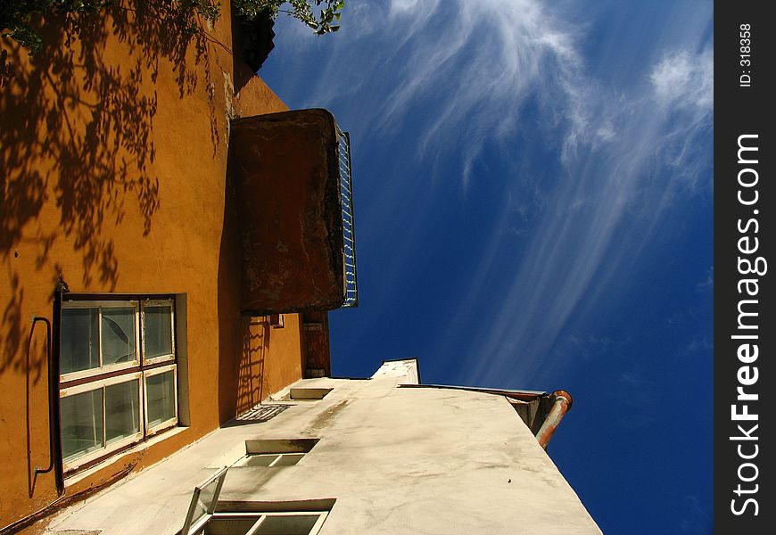 Three colored (blue-white-terracota) picture of the balcony seen from below, and the angled building. Three colored (blue-white-terracota) picture of the balcony seen from below, and the angled building