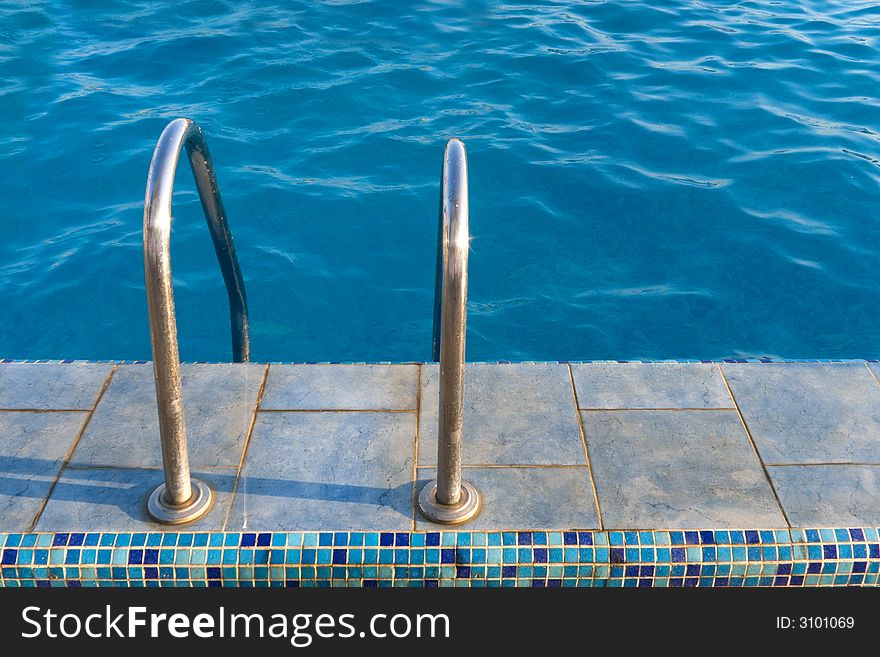 Metal staircase to water in swimming pool. Metal staircase to water in swimming pool