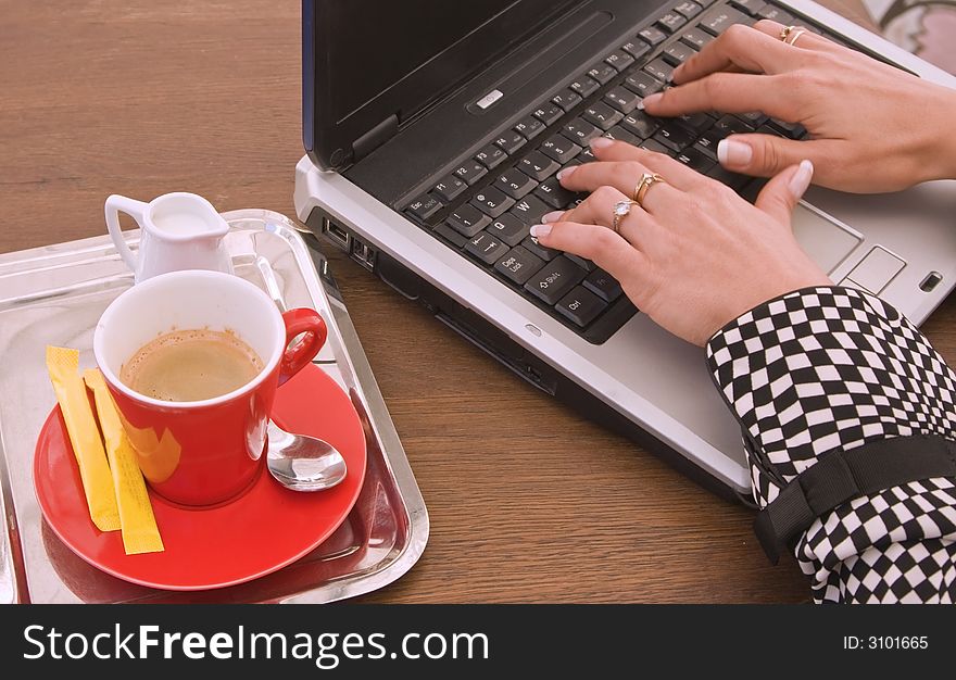 Detail image of woman's hands typing on a laptop at a coffee table. Detail image of woman's hands typing on a laptop at a coffee table.