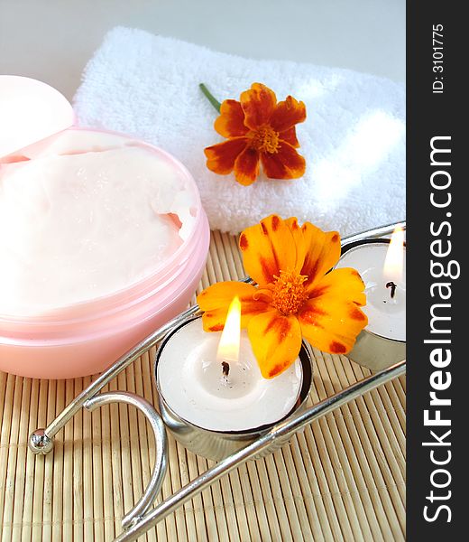 Cosmetic moisturizing cream and candle with flowers