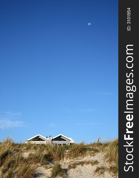 Moon over beach houses with gradient sky in background