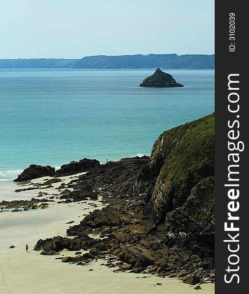 A deserted beach in brittany with a small island in the distance