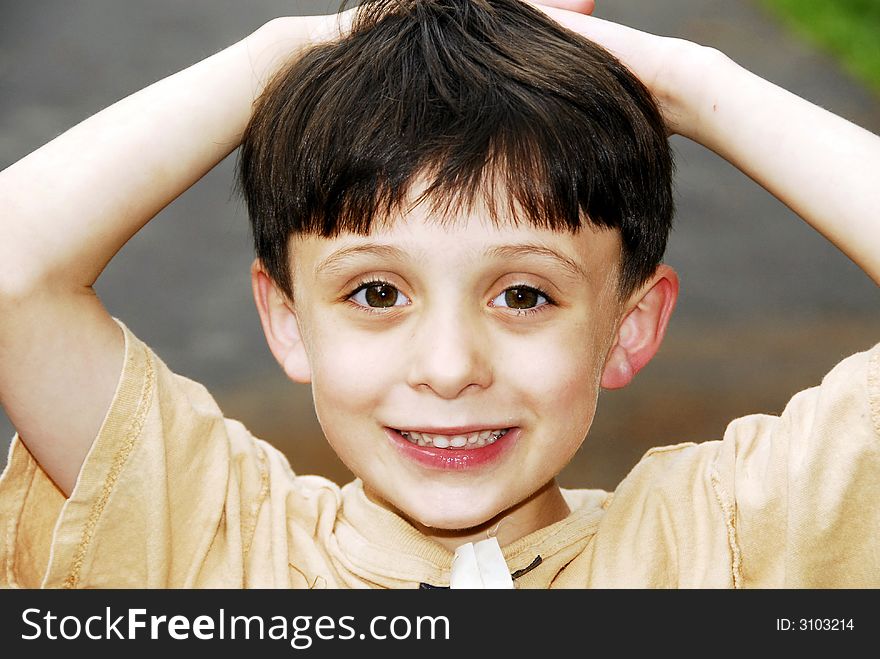 LIttle boy posing with a happy smile on his face and his hands on his head showing his perfect baby teeth. LIttle boy posing with a happy smile on his face and his hands on his head showing his perfect baby teeth