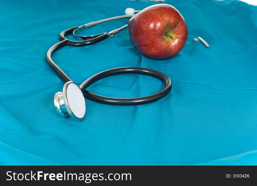 Stethoscope and apple lying on a green surgical scrub top
