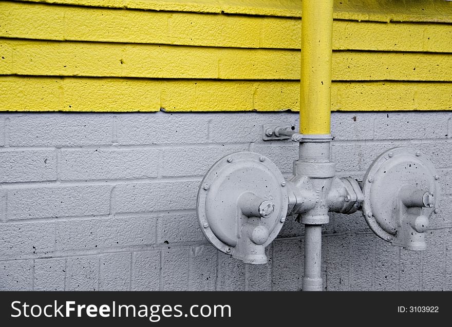 Industrial pipes on a cement wall with yellow painted strips. Industrial pipes on a cement wall with yellow painted strips.