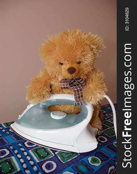 A teddy beard placed on an ironing board, ironing. A teddy beard placed on an ironing board, ironing