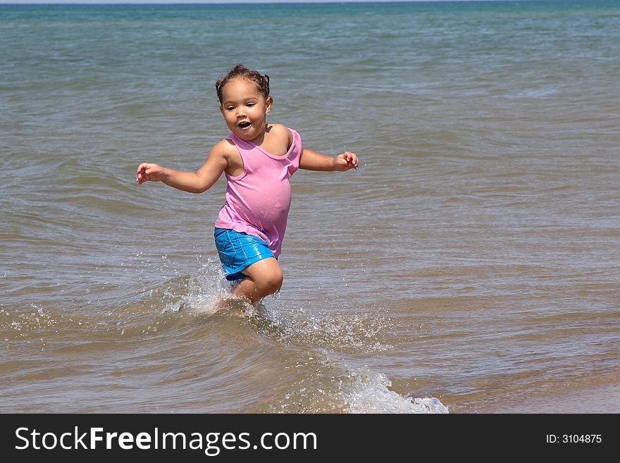 Little toddler girl running in the waves of Lake Michigan