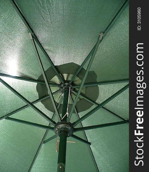 Under the green umbrella hiding from the strong sunlight