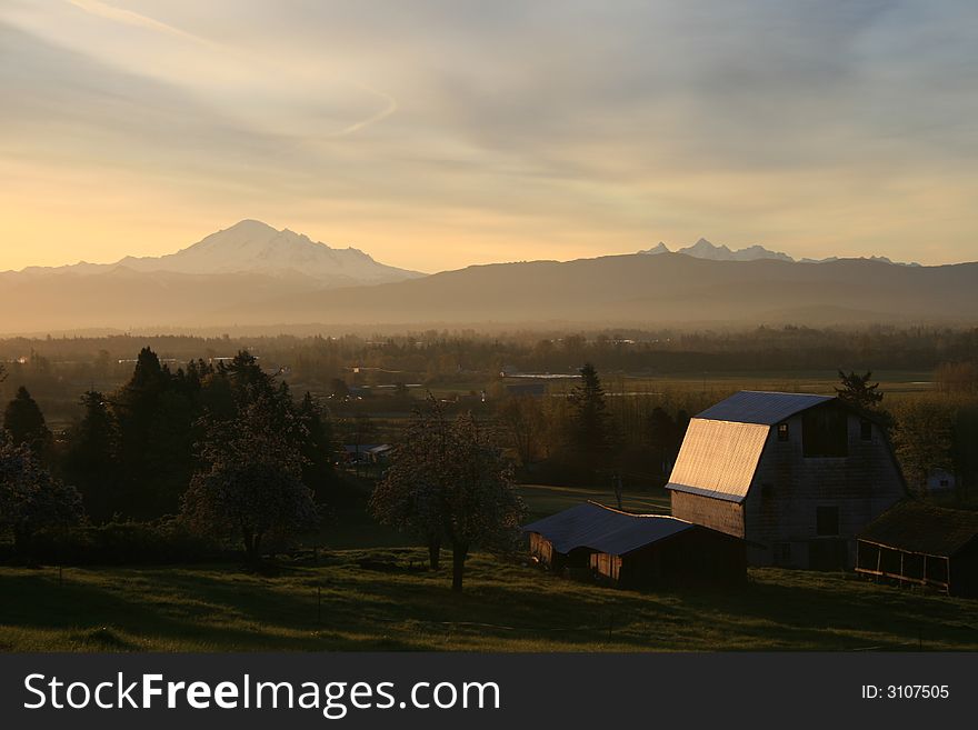 Sun rises over the mountains, lighting up a barn and pasture. Sun rises over the mountains, lighting up a barn and pasture