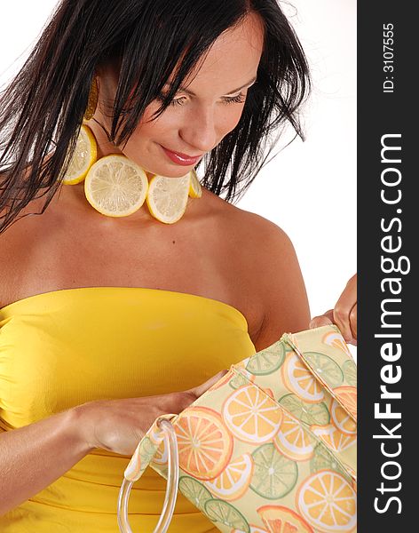 Girl wearing lemon necklace, looking inside handbag. Girl wearing lemon necklace, looking inside handbag.