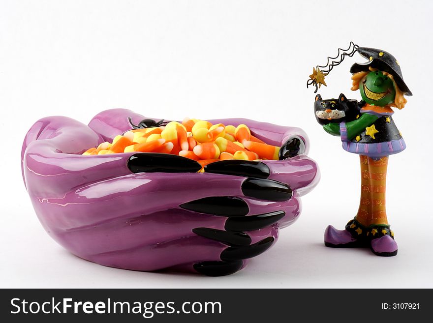 Halloween witch standing next to a bowl filled with candy. Halloween witch standing next to a bowl filled with candy.