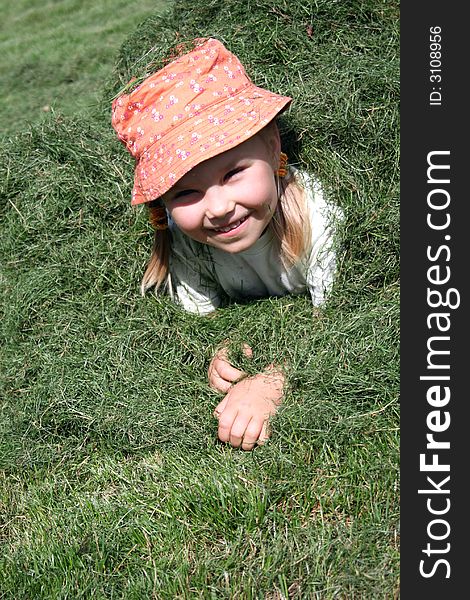 A girl having fun in a heap of just cut grass. A girl having fun in a heap of just cut grass