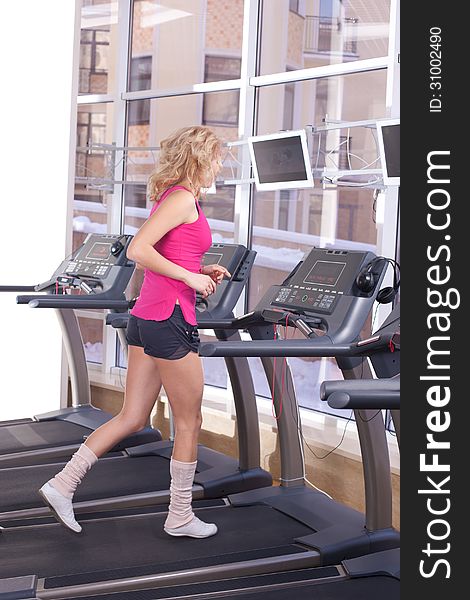 Attractive woman in pink sportswear running on treadmill at gym. Attractive woman in pink sportswear running on treadmill at gym