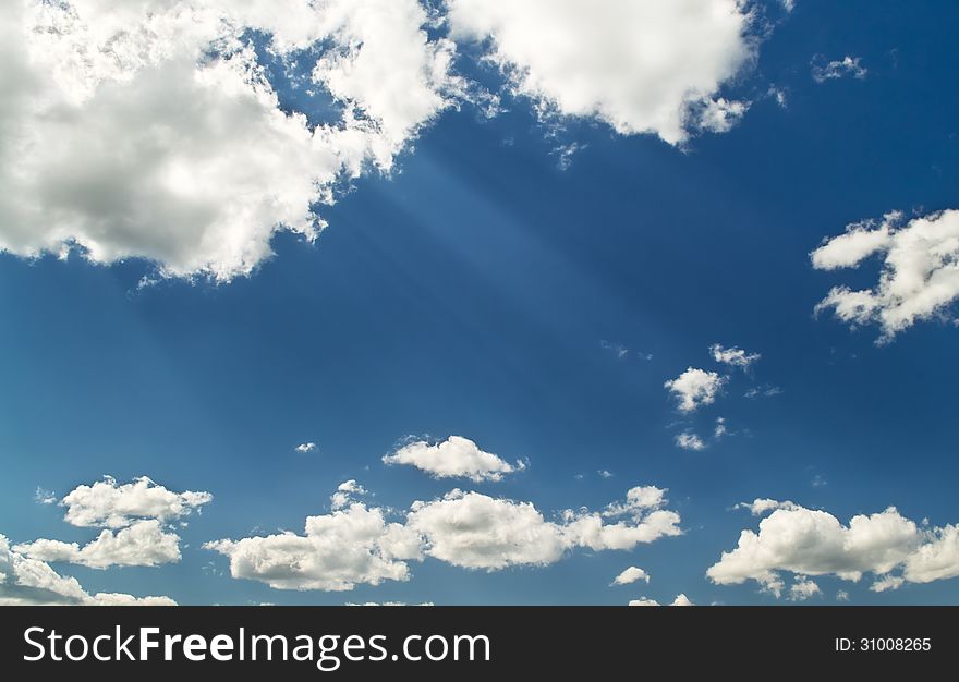 Bright blue cloudy sky with sunbeams from clouds