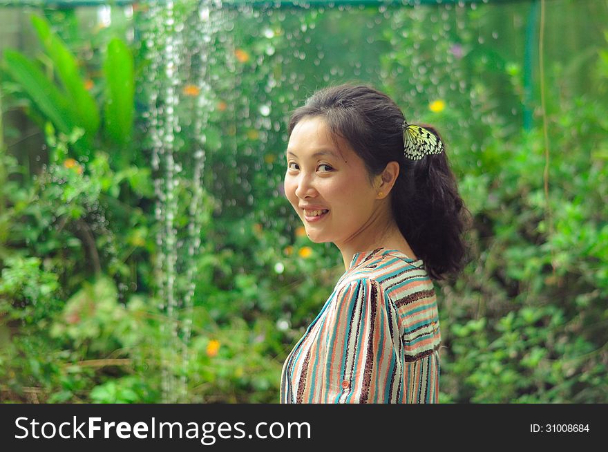 Portrait of single young girl smiling at camera with a white butterfly clings to her hair in a garden. Shot in Butterfly Valley, Bohol, Philippines. Portrait of single young girl smiling at camera with a white butterfly clings to her hair in a garden. Shot in Butterfly Valley, Bohol, Philippines.