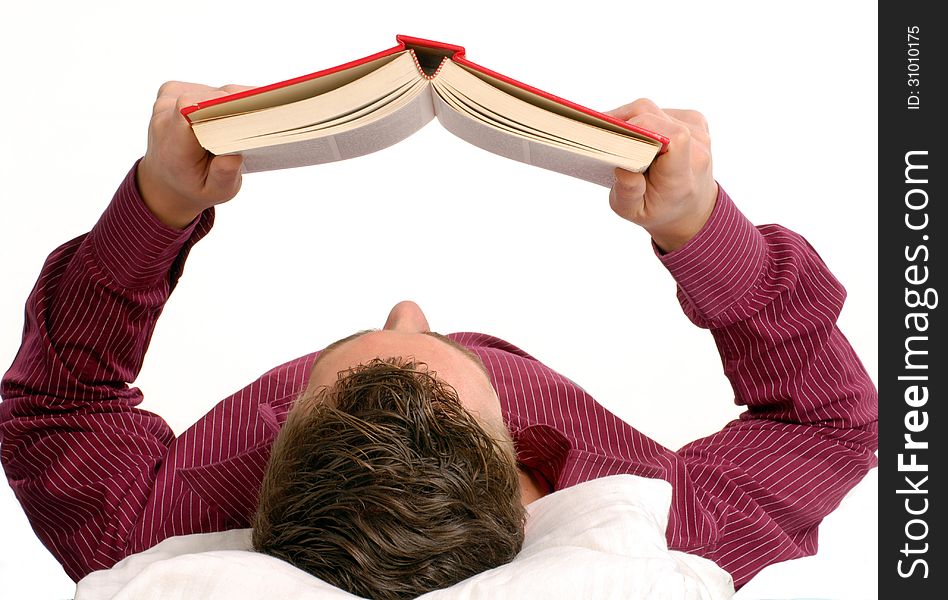 Young man lying down reading a book on bed. Young man lying down reading a book on bed.