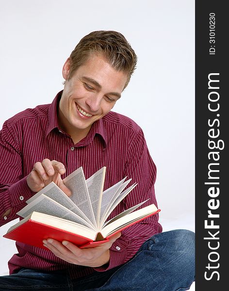 Happy young man holding and reading a red book. Happy young man holding and reading a red book.