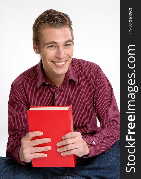 Happy young man holding and reading a red book. Happy young man holding and reading a red book.