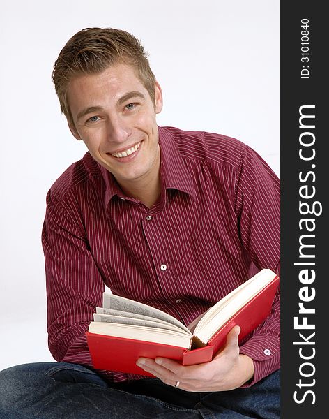 Happy young man holding and reading a book. Happy young man holding and reading a book.