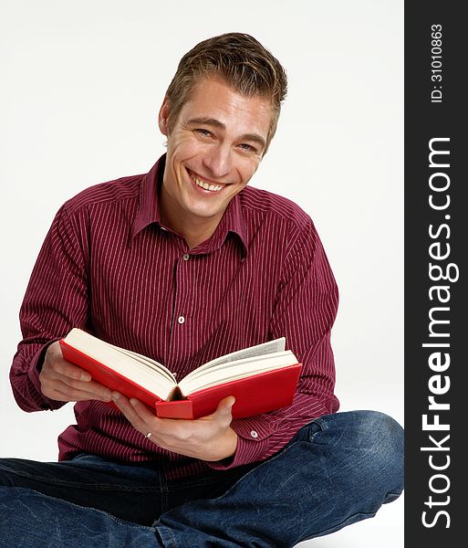 Happy young man holding and reading a book. Happy young man holding and reading a book.