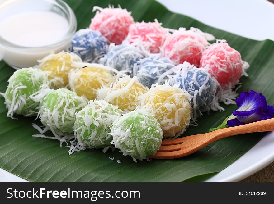 Kanomtom is Thai dessert made from rice powder stuffed with sweet coconut jam and sprinkled with grated coconut. Each color extracted from natural flowers. Presented on a piece of banana leaf. Kanomtom is Thai dessert made from rice powder stuffed with sweet coconut jam and sprinkled with grated coconut. Each color extracted from natural flowers. Presented on a piece of banana leaf.